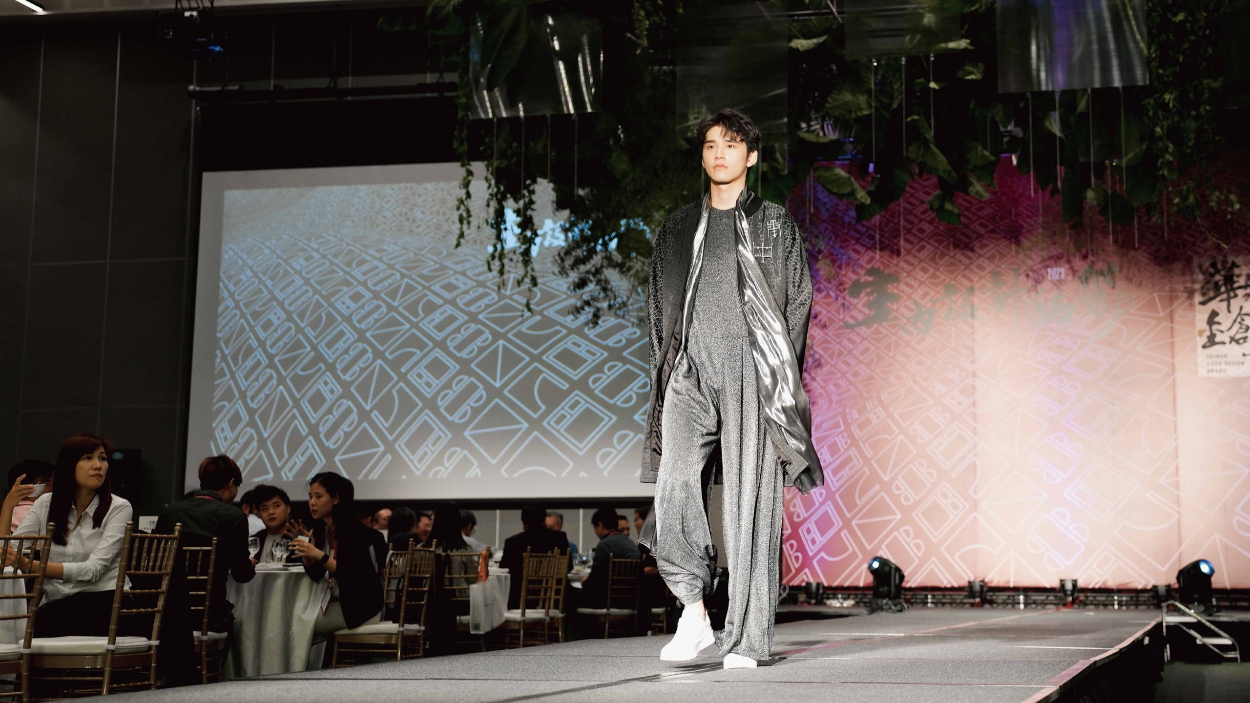 2023 華之金創獎時裝秀：男模身著銀灰針織連身褲搭配提花長外套走秀